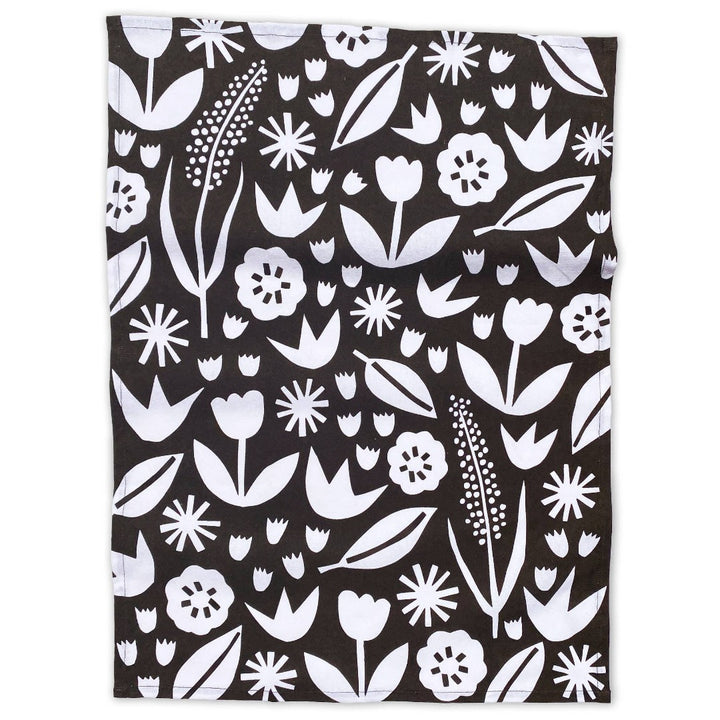 A flat lay of a black and white cotton tea towel with an abstract floral print.