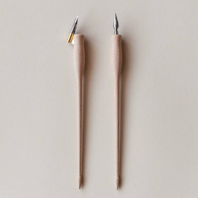 Two wooden calligraphy tools with examples of tips for writting.