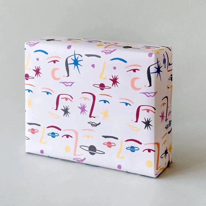 white wrapping paper with colourful faces all over with planets and stars