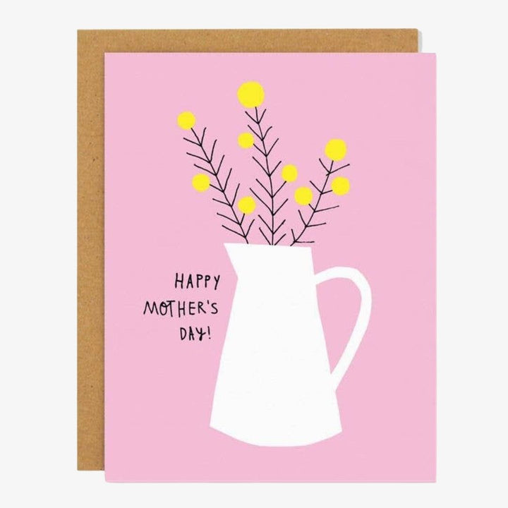 A pink card with a white jug with yellow flowers reading Happy Mother's Day! in black.