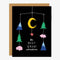 A black card with a mobile with a yellow moon, red star, blue mountains, green pine trees and pink clouds reading 