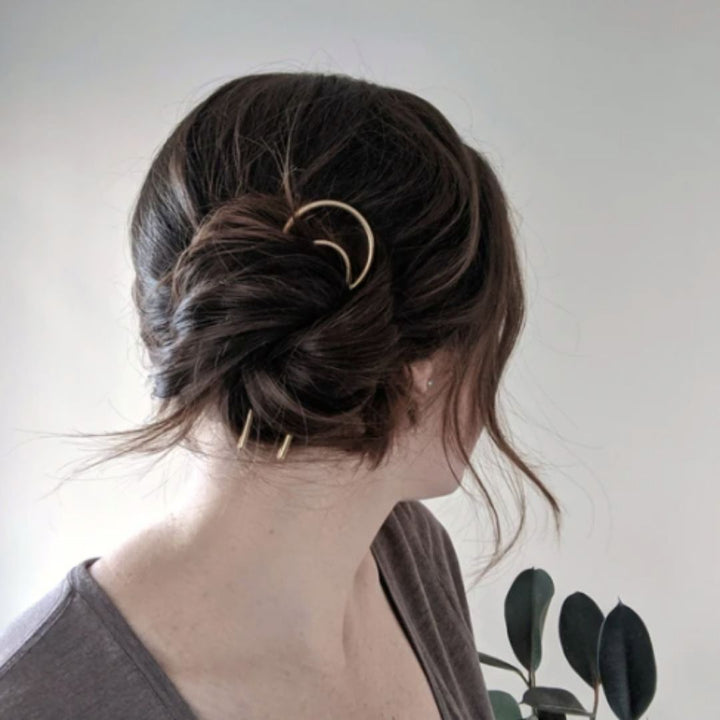 Brass crescent hair fork in womans hair. 