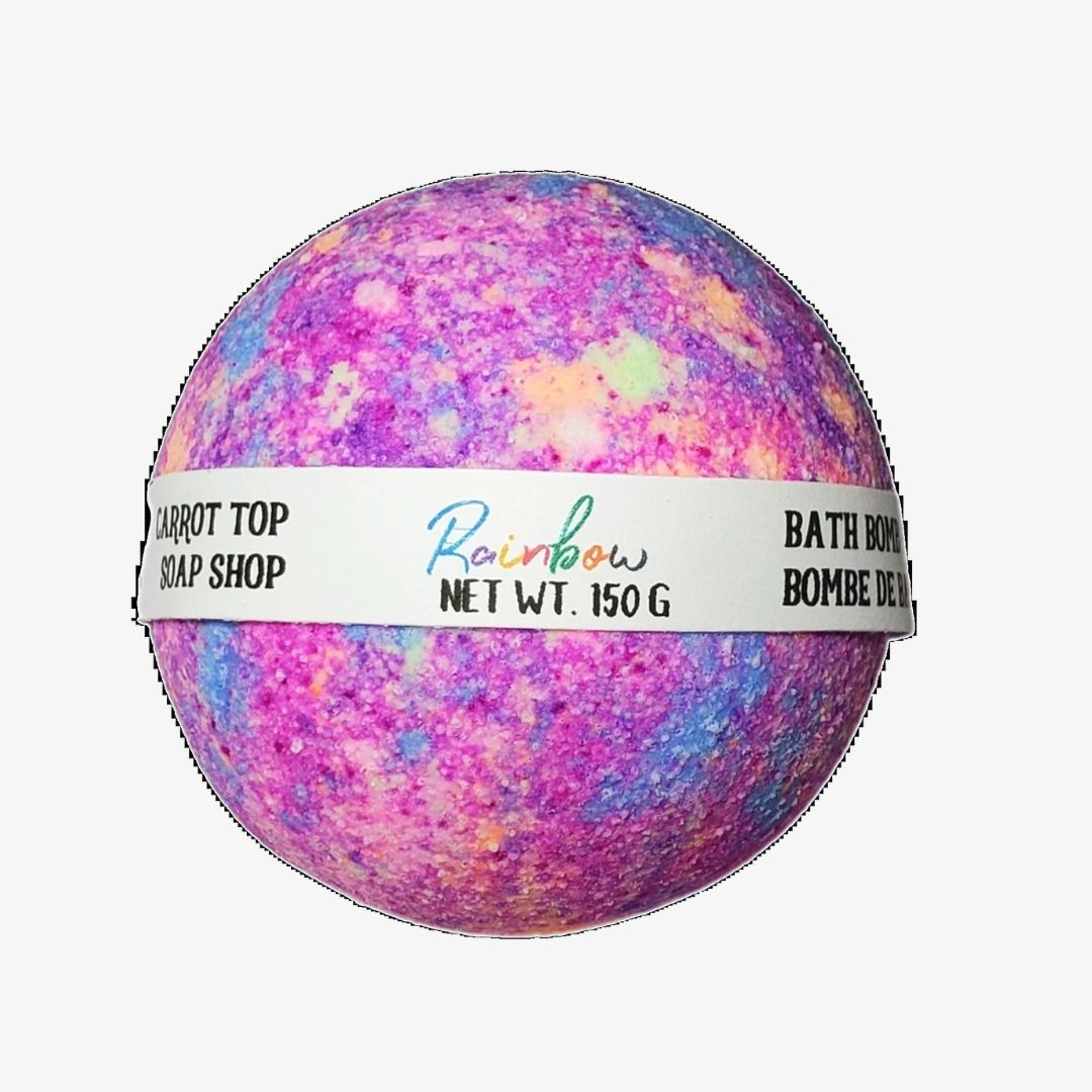 A multicolored bath bomb with purple, pink, and blue hues, packaged with a label that reads 'Rainbow NET WT. 150g'.