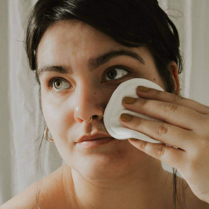 Woman wiping face with reusable makeup remover pad