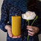 A woman is holding a peony and a fluted beeswax pillar candle.