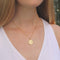 Woman wearing a gold coin necklace with a crown printed on it