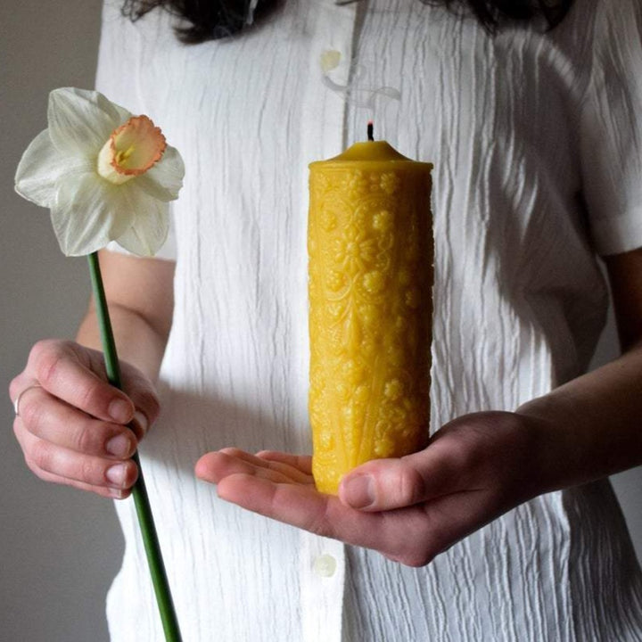Girl holding natural beeswax pillar candle with floral pattern
